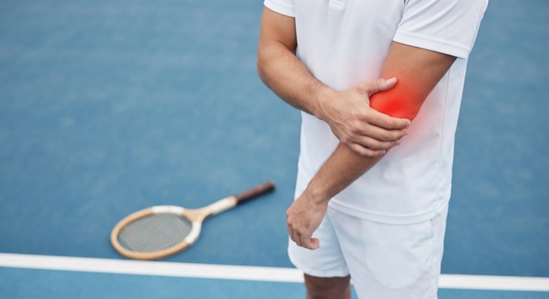 Tennis player holding a sore elbow on the court